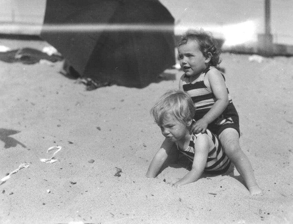 Marilyn Monroe as a child on the beach with her mother in 1929, capturing a timeless moment of innocence and joy.