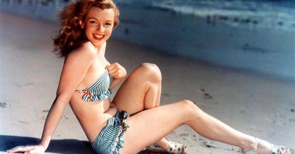 Iconic actress Marilyn Monroe posing on a sandy beach, exuding timeless elegance and charm in a classic modeling session